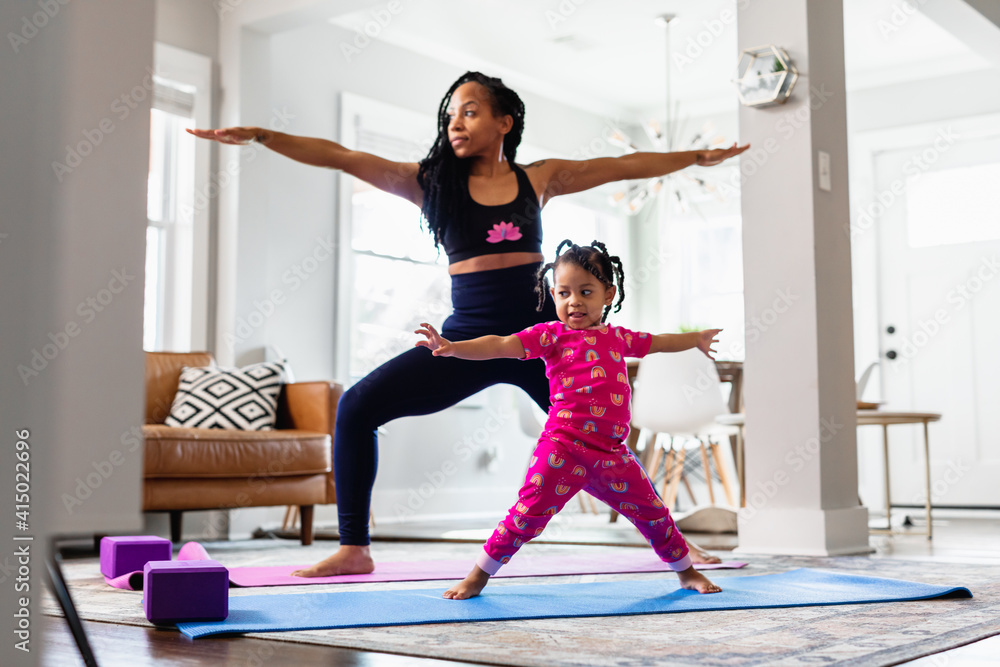 Black Mother and daughter doing yoga in family room, warrior pose Stock ...