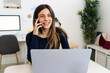 © Giorgio Fochesato/Westend61 - Young female student with laptop laughing while talking on smart phone in living room