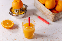 Glass Of Orange Juice With Spoon And Stainless Steel Juicer On Modern Marble