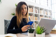 © Giorgio Fochesato/Westend61 - Smiling student with laptop holding smart phone while studying at home