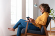 © steve brookland/Westend61 - Mid adult woman with digital tablet looking away while sitting on armchair at home