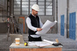 © Veam/Westend61 - Male architect analyzing blueprint while standing at table in building