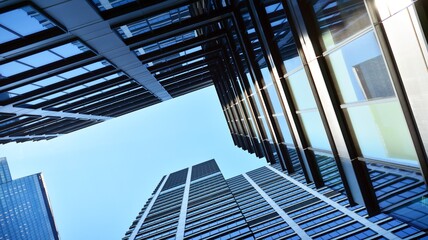 Bottom view of modern skyscrapers in business district against blue sky. Looking up at business buildings in downtown.