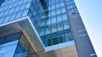 Facade texture of a glass mirrored office building. A beautiful background of an glass office building, reflecting clouds in the windows.