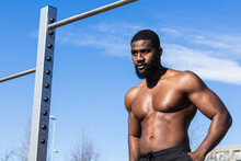 Shirtless Muscular Black Male Athlete Standing Hands On Hips Resting During Workout In Sunlight