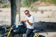 © Oscar Gimbal/ADDICTIVE STOCK - Stylish male biker sitting on modern motorcycle in urban area and looking at camera