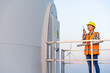 © geargodz - female engineer using walkie talkie to checking system against wind turbine farm