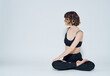 © SHOTPRIME STUDIO - A woman in leggings sits cross-legged on the floor and turns to the sides