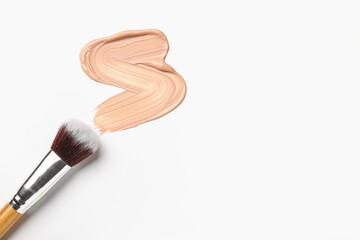 Sample of makeup foundation and brush on white background