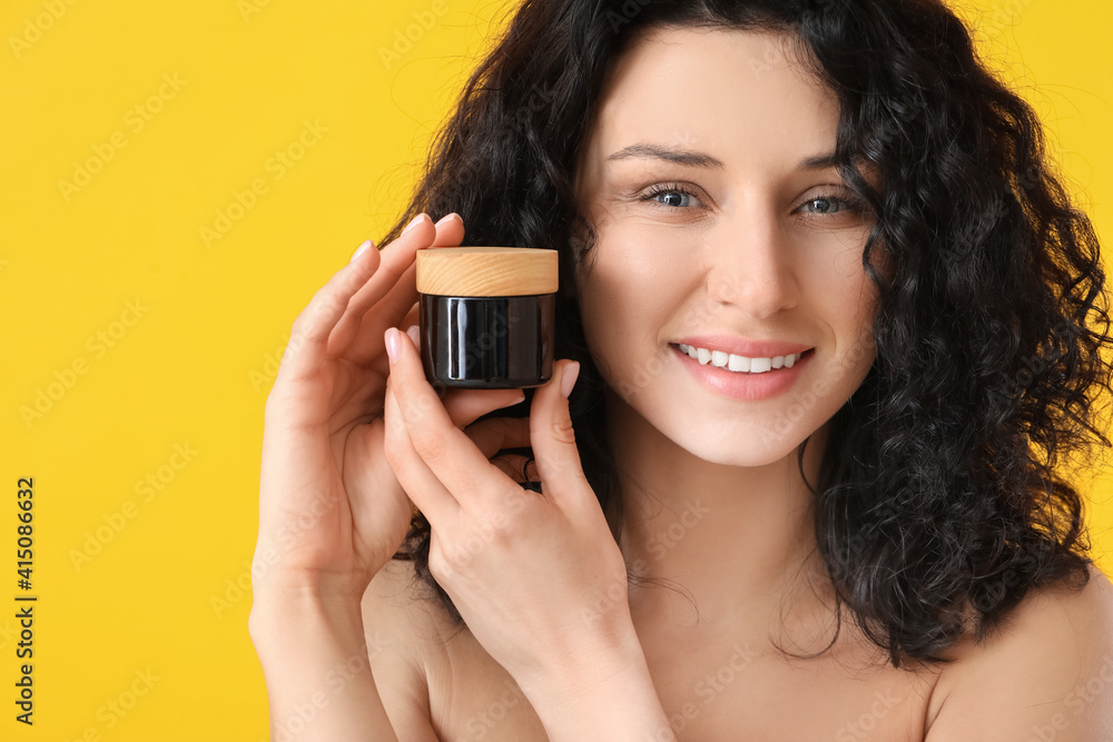 Beautiful young woman with cream on color background