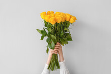 Female Hands With Beautiful Yellow Roses On Light Background