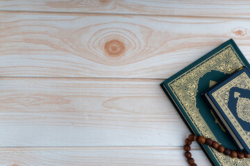 Poster - Holy Quran with arabic calligraphies translation meaning of Al-Quran and Rosary or Tasbih on wooden background. Ramadan,Hajj, Islamic and Copy Space concept