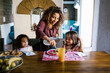 © Marcos - Hispanic mother serving breakfast to her daughters at home in Latin America