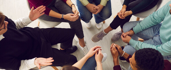 top view of diverse people sitting in a close circle and talking to a therapist. cropped image of un