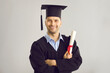 © Studio Romantic - Studio portrait of satisfied student with his graduation certificate. Happy academy, college or university graduate standing against gray background, holding his diploma scroll and smiling at camera