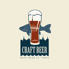 Wall Mural - Vector banner for craft beer with an overflowing glass of frothy beer, a fish and silhouettes of houses of old town in a retro style and with words Craft beer. Best beer in town