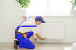 © Angelov - Plumber man is blocking repairs radiators of heating battery in apartment tap