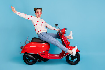 Sticker - Full length photo of crazy girl ride moped raise hand wear heart print pullover jeans sneakers isolated blue color background