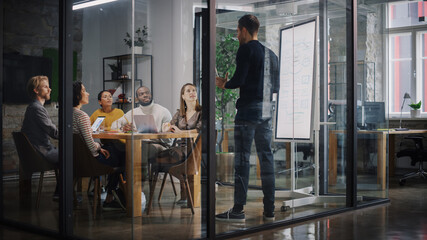 Aufkleber - Project Manager Makes a Presentation for a Young Diverse Creative Team in Meeting Room in an Agency. Colleagues Sit Behind Conference Table and Discuss Business Development, User Interface and Design.
