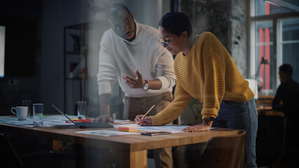 Wall Mural - Two Diverse Multiethnic Colleagues Have a Conversation in a Meeting Room Behind Glass Walls in an Agency. African American Creative Director and Female Project Manager Discuss Work on Laptop Computer.