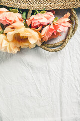Wall Mural - flat-lay of beautiful peony flowers in straw bag over grey linen table cloth background