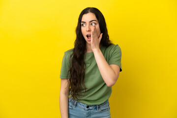 Wall Mural - Young caucasian woman isolated on yellow background whispering something with surprise gesture while looking to the side