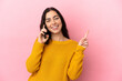© luismolinero - Young caucasian woman using mobile phone isolated on pink background showing and lifting a finger in sign of the best