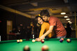 © liderina - Young couple spending time in billiard room. Boyfriend teaching his girlfriend to playing billiard.