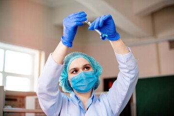 Scientist researching in laboratory. Focused female science professional holding blue solution into the glass cuvette. Healthcare and biotechnology concept.