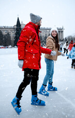 Poster - Happy young couple skating at outdoor ice rink