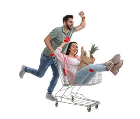 Sticker - Young man giving his girlfriend ride in shopping cart with groceries on white background