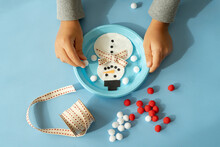 Hands Of Child Creating A Snowman With Ribbon And Pompom At Christmas Time
