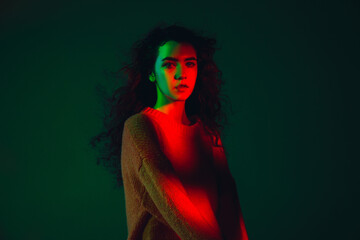 Pretty. Caucasian woman's portrait isolated on green studio background in multicolored neon light. Beautiful female model. Concept of human emotions, facial expression, sales, ad, fashion. Copyspace.