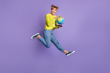 Poster - Full length body size view of lovely cheerful girl jumping holding globe learning countries isolated on violet color background