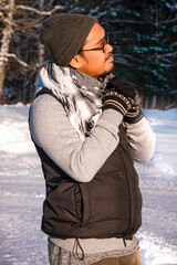 Person standing outside in winter holding his hands togheter and looking at something in the sun