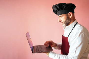 Chef man with laptop with pink background