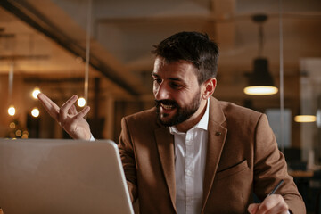 Wall Mural - Young businessman using laptop in his office. Happy man working on computer at his workplace.