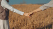 Woman and man holding hands on a golden yellow meadow. Backdrop are shadows of both of them on the ground. Feelings of love and romance. Ideas for Valentine's Day wallpaper with copy space.