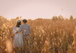 Woman and man stand together and tilt their heads against each other on a golden yellow meadow. Feelings of love and romance. There is copy space. Idea for Valentine's wallpaper with copy space.