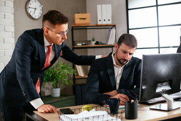 colleagues working in the office. two businessman discussing work and using computer in the office.