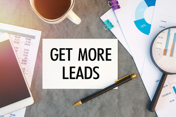 GET MORE LEADS is written in a document on the office desk, coffee, diagram and smartfon