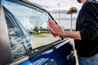 © AliciaFdez - Detalle de un hombre joven limpiando el cristal de la ventanilla de su coche con un paño de microfibra rosa