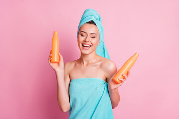 Sticker - Photo of smiling laughing young woman wear blue turban holding two balm bottles isolated pastel pink color background