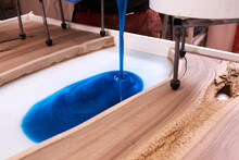 Process Making Of A Craft Resin And Wood Table. Liquid Epoxy Is Poured Into A Mold With Wooden Blanks.