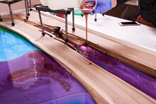 Process Making Of A Craft Resin And Wood Table. Liquid Epoxy Is Poured Into A Mold With Wooden Blanks.