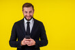 © yurakrasil - Portrait of young handsome man talking on the phone, holding smartphone next to ear isolated on yellow background