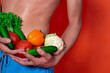 © Denis - A beautiful male body and natural vegetables. Diet and nutrition. Orange background. Broccoli, tomatoes, cucumbers, peppers and lettuce.