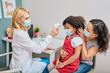 © Peakstock - General practitioner using infrared thermometer measures female kid body temperature during a pandemic