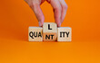 Quality over quantity symbol. Businessman turns cubes and changes the word 'quantity' to 'quality'. Beautiful orange table, orange background, copy space. Business and quality over quantity concept.