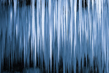 Beautiful Long Icicles Of A Frozen Waterfall, With Water Flowing And Crashing Down And Ice Water Dripping From The Tips Of Icicles In A Cold Eery And Moody Atmosphere In A Cave In The Mountains 